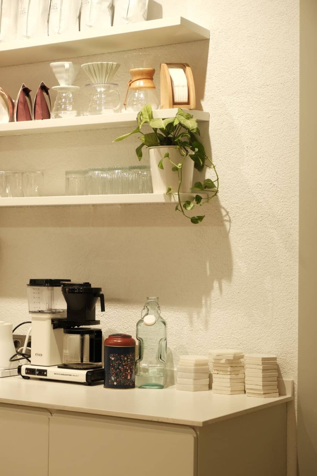 A tidy kitchen counter with a coffee maker, mugs, and glassware, stocked and ready