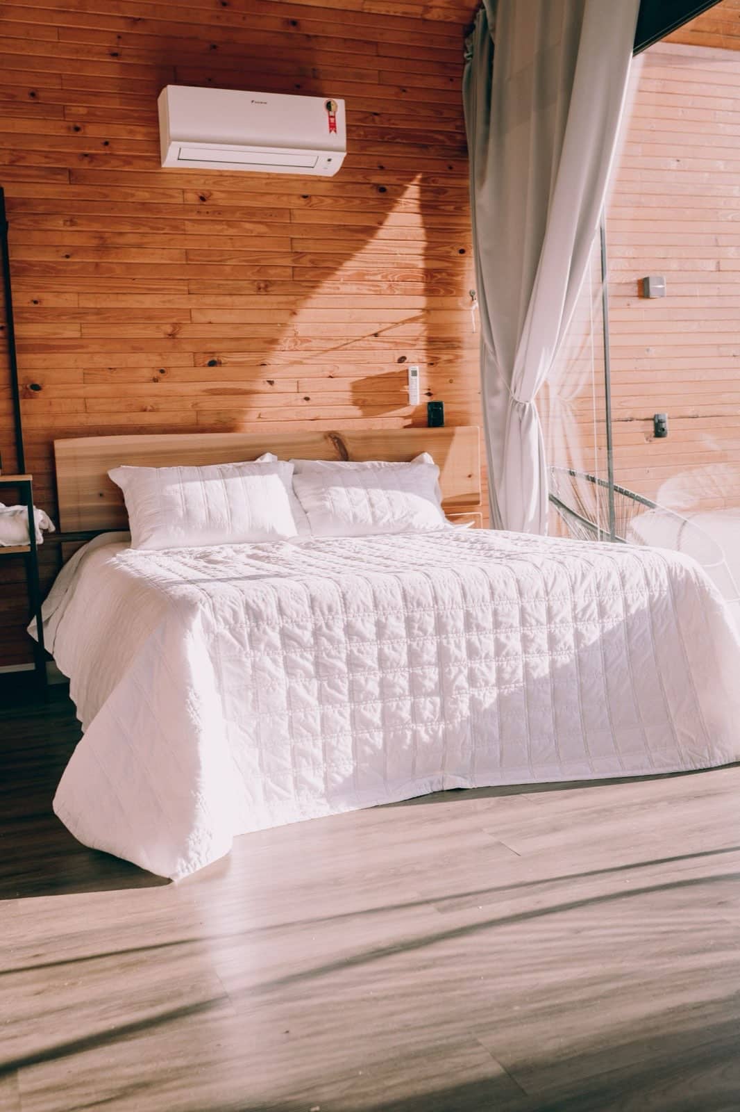 A neatly made bed with crisp white linens in a bright, clean bedroom